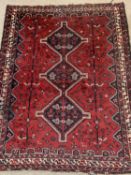 PERSIAN RED GROUND HANDMADE WOOL RUG, triple medallion centre, geometric border, 210 x 168cms