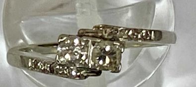 18CT PLATINUM CROSSOVER DIAMOND RING, two central 0.10ct round stones in square settings with