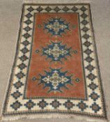 EASTERN WOOLEN RUG, cream and rust ground with tasselled ends, multiple border and a tri-central