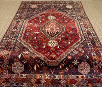 SHIRAZ RUG, hexagonal madder field with central medallion, six repeating hooked guls, multiple