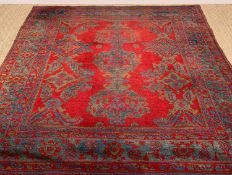 TURKISH OUSHAK SQUARE RUG, woven wool with blue and green linked designs to madder field, broad