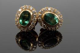 PAIR OF YELLOW METAL EMERALD & DIAMOND CLUSTER EARRINGS, the central rubover set oval emeralds