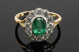 18CT GOLD EMERALD & DIAMOND CLUSTER RING, the central oval faceted emerald (8 x 6mms approx.) with a