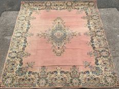 WOOLEN RUG, salmon pink ground with floral pattern and star motif to centre, 360 x 274cms