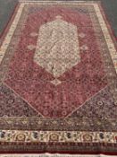 LARGE PERSIAN WOOLLEN CARPET of red ground, floral and abstract pattern throughout, 615 x 330cms