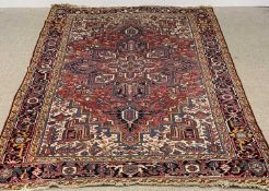 PERSIAN WOOLLEN RUG of red ground, abstract patterns throughout with central star shaped design, 295