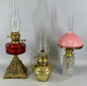 THREE VICTORIAN OIL LAMPS, the first having pierced cast metal base, faceted cranberry glass