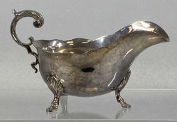 GEORGE V SILVER SAUCE BOAT having wavy rim, acanthus capped scroll handle on three hoof feet,