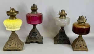 FOUR CAST METAL BASE OIL LAMPS, pink, yellow and clear glass reservoirs, 37cms (h) the tallest
