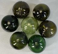 SEVEN HAND BLOWN GREEN GLASS FISHING FLOATS, each approx. 13cms (diam.) Provenance: private
