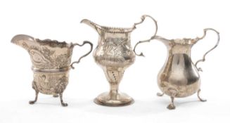 THREE SILVER MILK JUGS, comprising George III baluster jug on three feet, base engraved with cursive