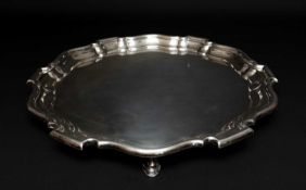 GEORGE V SILVER SALVER, of circular shape with shaped rim, raised on three feet, Sheffield 1919,