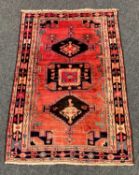 LURI RUG, three geometric medallions to a madder field, geometric border and guards, 225 x 145cms