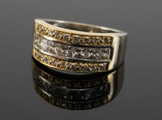 18CT GOLD DIAMOND CLUSTER RING, channel set with 7 princess cut stones bordered by 18 round