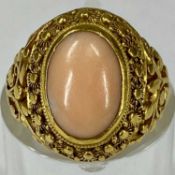 OVAL CABOCHON CORAL RING with ornate pierced and chased yellow metal mount, size F, 7gms Provenance: