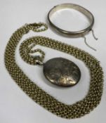 SILVER HOLLOW BANGLE with scrolling engraved decoration, and an oval silver locket, engraved with