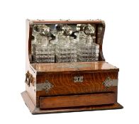 EARLY 20TH CENTURY OAK & PLATE MOUNTED THREE BOTTLE TANTALUS, fitted with whisky decanters before