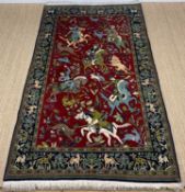 MODERN KASHAN STYLE HUNTING RUG, decorated with mounted huntsmen and wild animals on a madder field,