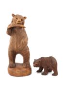 TWO MODERN BLACK FOREST CARVED BEARS, one standing and eating a salmon, 39cms (h), the other smaller