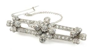 WHITE METAL DIAMOND ENCRUSTED TRIPLE FLOWERHEAD BAR BROOCH, the seven principal stones measuring 1.