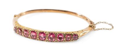 YELLOW METAL PASTE & DIAMOND CHIP HINGED BANGLE, having nine graduated oval pink paste stones,