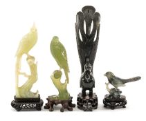 FOUR CHINESE CARVED HARDSTONE MODELS OF BIRDS, two perched on wooden stumps in pale green stone, one