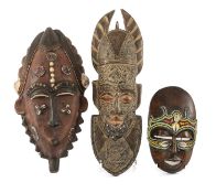 THREE AFRICAN DECORATIVE MASKS including Baule style mask with cowrie and beaded ornament, the