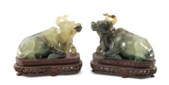 PAIR OF CHINESE GREEN HARDSTONE CARVINGS of recumbent buffaloes, on carved hardwood stands, 12cms (