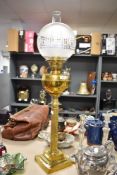 A Victorian oil lamp having ridged brass column over stepped foot, with frosted glass shade having
