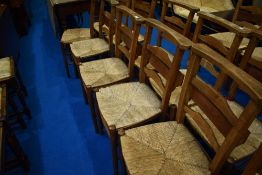 A set of six rush seated chapel chairs having ladder backs, with hymn/prayer book shelves