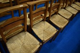 A set of six rush seated chapel chairs having ladder backs, with hymn/prayer book shelves