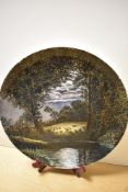 A 20th Century studio pottery charger, decorated with a moonlit scene depicting sheep in a field,