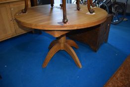 A modern golden oak extending dining table on turned pedestal with butterfly centre leaf, diameter