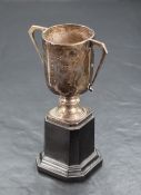 A George V silver trophy, of two-handled cylindrical form with short knopped stem and canted
