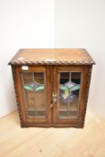 A late 19th Century oak smoker's cabinet, with leaded and stained glass panelled doors, having a
