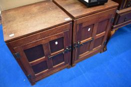 A pair of Arts and Crafts oak bedside cabinets with medieval style panelled doors and metalwork