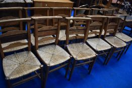 A set of twelve traditional rush seated chapel chairs having book rests to back