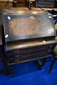 An early 20th Century Queen Anne style wanut bureau of small proportions having drop flap over three