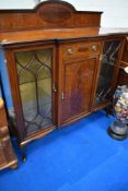 An Edwardian mahogany display cabinet with central drawer over cupboard, flanked by dual display
