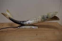 A vintage horn lamp, in the form of a fish, having carved features.