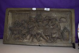 A resin moulded wall plaque, depicting a Dutch tavern scene, measuring 25cm x 50cm overall