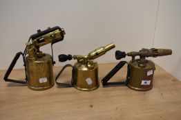 A trio of vintage brass blow torches.
