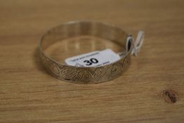 A white metal buckle form bangle with engraved decoration