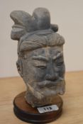 A cast terracotta Chinese warrior head on wood plinth.