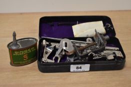 A vintage Singer sewing machine tin, containing a selection of Singer sewing machine attachments,