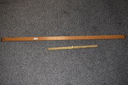 A vintage yard stick and a folding meter rule.