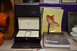 A Patek Phillipe case and box, a selection of magazines and a book.
