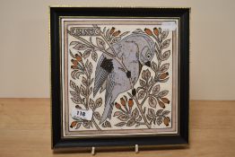 A framed tile of tube lined design, depicting bird in branch.