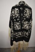 A vintage fringed shawl, having white embroidered bird and flower design on black ground.