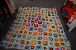 A large bright and cheerful vintage crocheted blanket, having raised flowers to each square and